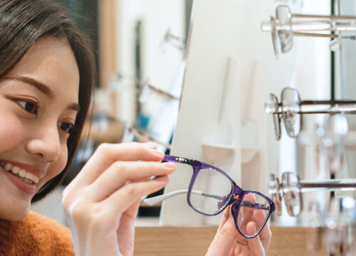 Photo of a young woman looking at glasses at the optometrist